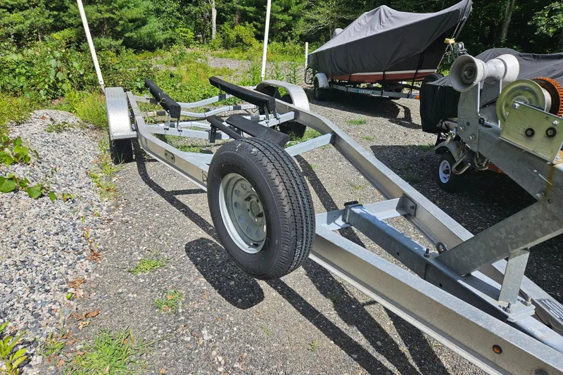 Slide: The Image of Boat trailer for 2005 Topaz 24 Silverhawk, parked on gravel with covered boat in background. - 41