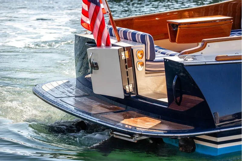 Slide: The Image of 2017 Hinckley Picnic Boat MKIII with American flag, elegant wooden deck, and striped seating. - 12