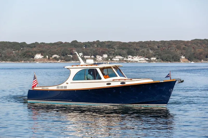 Slide: The Image of 2017 Hinckley Picnic Boat MKIII cruising on calm waters near a wooded shoreline. - 2