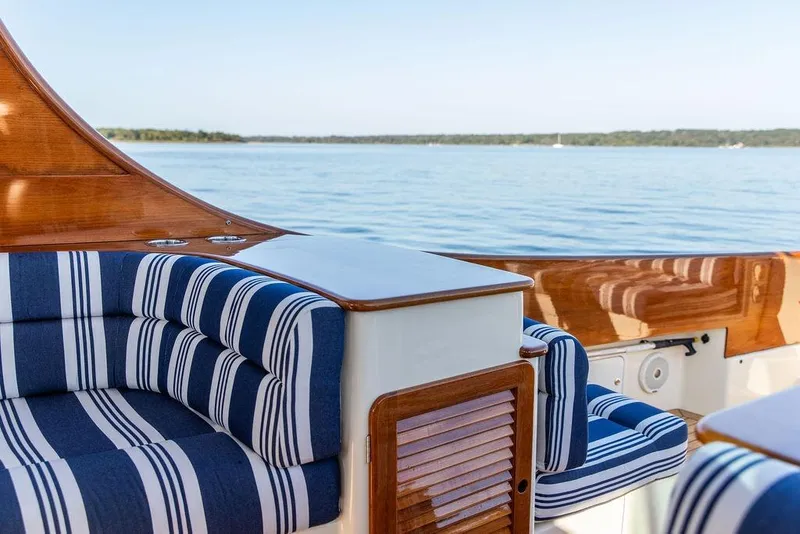 Slide: The Image of 2017 Hinckley Picnic Boat MKIII with striped seating, wooden accents, and scenic water view. - 20