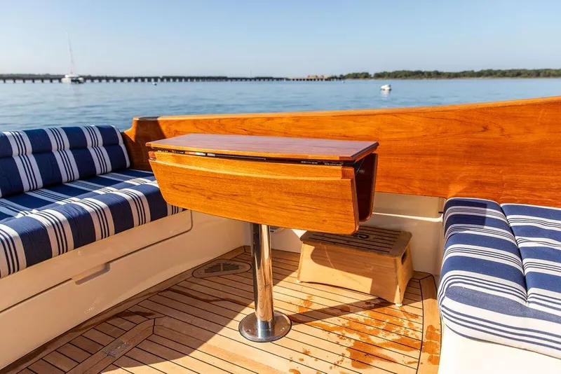 Slide: The Image of Hinckley Picnic Boat MKIII 2017 interior with striped seating and wooden table on deck. - 22