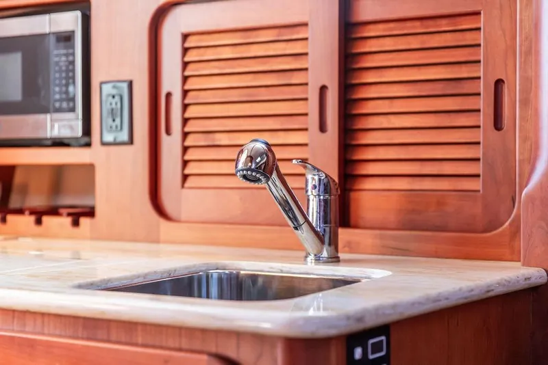 Slide: The Image of Hinckley Picnic Boat MKIII 2017 kitchen with wooden cabinets, stainless steel sink, and microwave. - 39