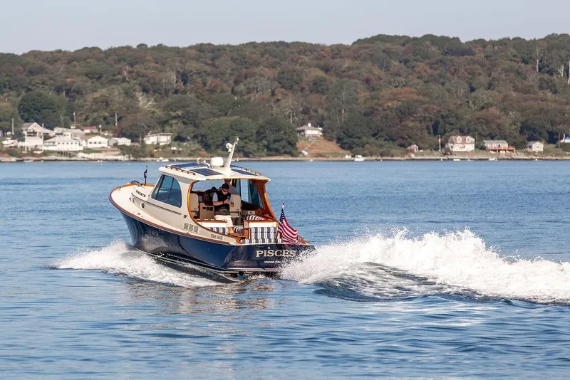 Slide: The Image of 2017 Hinckley Picnic Boat MKIII cruising on a scenic lake with shoreline houses. - 4