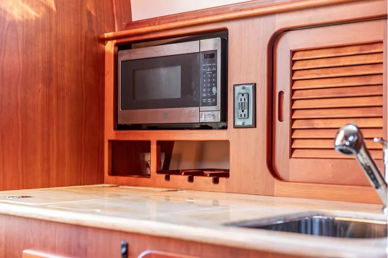 Slide: The Image of Hinckley Picnic Boat MKIII 2017 interior with microwave, wooden cabinetry, and sink. - 40