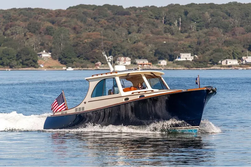 Slide: The Image of 2017 Hinckley Picnic Boat MKIII cruising on a scenic lake with shoreline houses. - 9