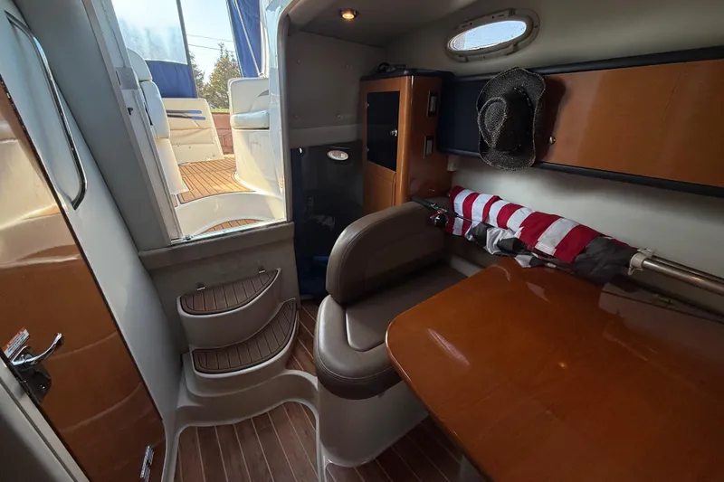 Slide: The Image of 2009 Chaparral Signature 280 cabin interior with wooden table, seating, and nautical decor. - 23