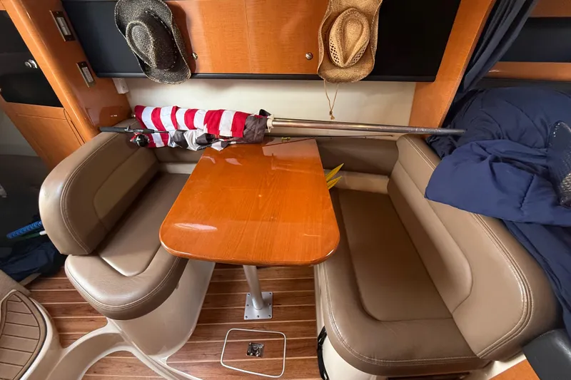 Slide: The Image of Interior of 2009 Chaparral Signature 280 with wooden table, leather seating, and hats on the wall. - 36