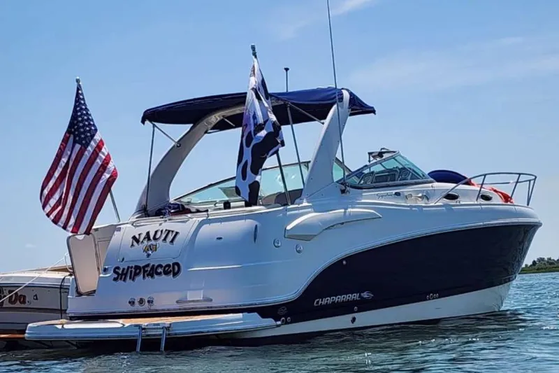 Slide: The Image of 2009 Chaparral Signature 280 boat with flags, named "Nauti Shipfaced," on the water. - 5