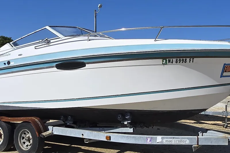 Slide: The Image of 1992 Wellcraft Eclipse 233 boat on trailer, white with blue accents, clear sky background. - 6