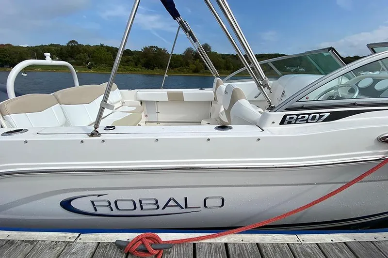 Slide: The Image of 2019 Robalo R207 Dual Console boat docked by a scenic lake. - 10