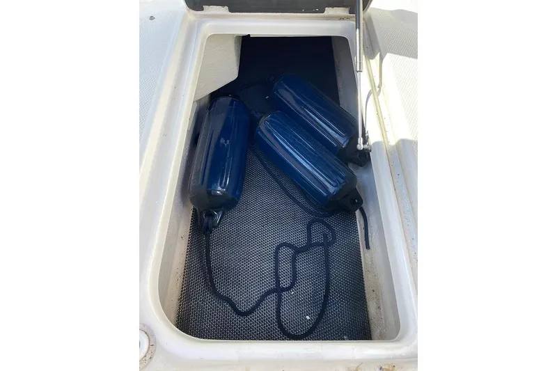 Slide: The Image of Storage compartment with blue fenders on a 2019 Robalo R207 Dual Console boat. - 16