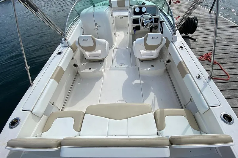 Slide: The Image of 2019 Robalo R207 Dual Console boat interior with beige and white seating, docked by water. - 9