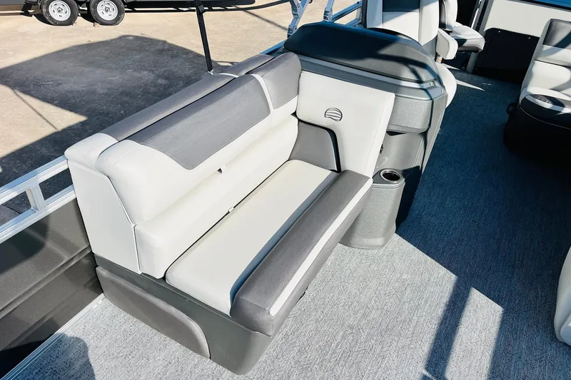 Slide: The Image of 2026 Sun Tracker Fishin' Barge 22 DLX interior seating with gray upholstery and cup holder. - 18