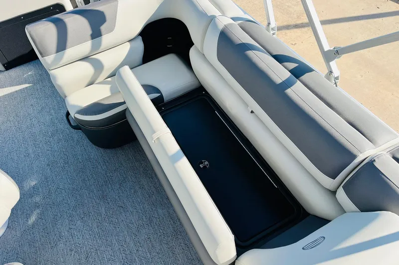 Slide: The Image of 2026 Sun Tracker Fishin' Barge 22 DLX interior seating with storage compartment open. - 25