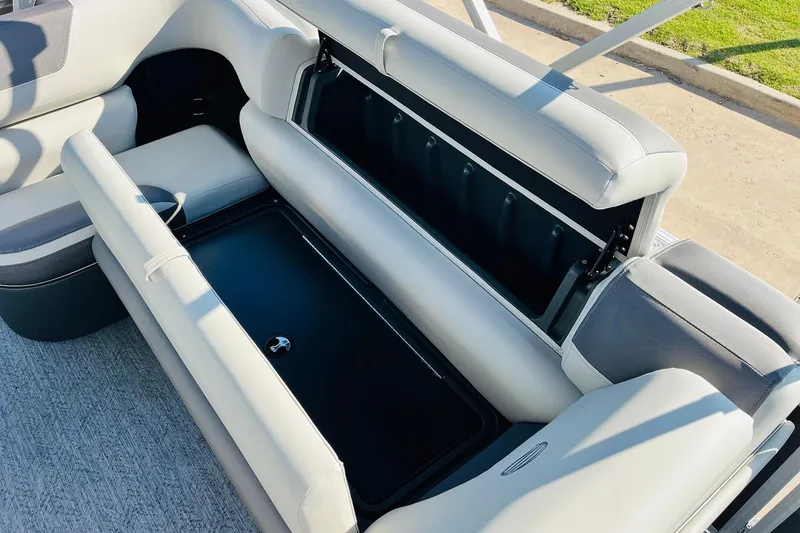 Slide: The Image of 2026 Sun Tracker Fishin' Barge 22 DLX interior storage compartment with cushioned seating. - 28