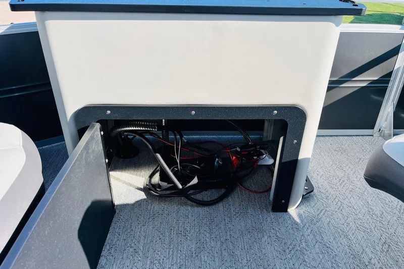 Slide: The Image of 2026 Sun Tracker Fishin' Barge 22 DLX storage compartment with visible wiring. - 51