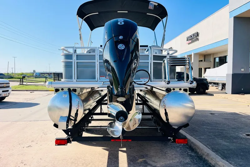 Slide: The Image of 2026 Sun Tracker Fishin' Barge 22 DLX pontoon boat with outboard motor, parked outdoors. - 6