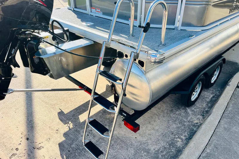 Slide: The Image of 2026 Sun Tracker Fishin' Barge 22 DLX with ladder and outboard motor on trailer. - 8