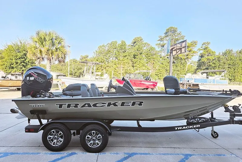 Slide: The Image of 2026 Tracker Pro Team 195 boat on trailer, parked outdoors with trees in background. - 7