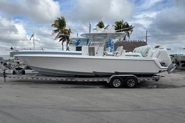 Slide: The Image of 2024 Contender 32 ST boat on trailer, parked outdoors with palm trees in background. - 1