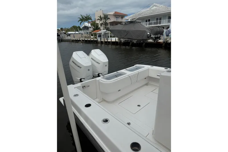 Slide: The Image of 2024 Contender 32 ST boat with dual Mercury engines docked by waterfront homes. - 14