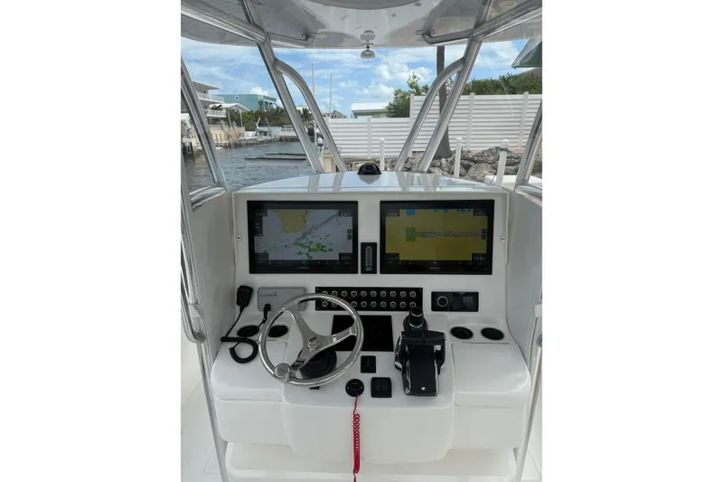 Slide: The Image of 2024 Contender 32 ST boat dashboard with navigation screens and steering wheel. - 16