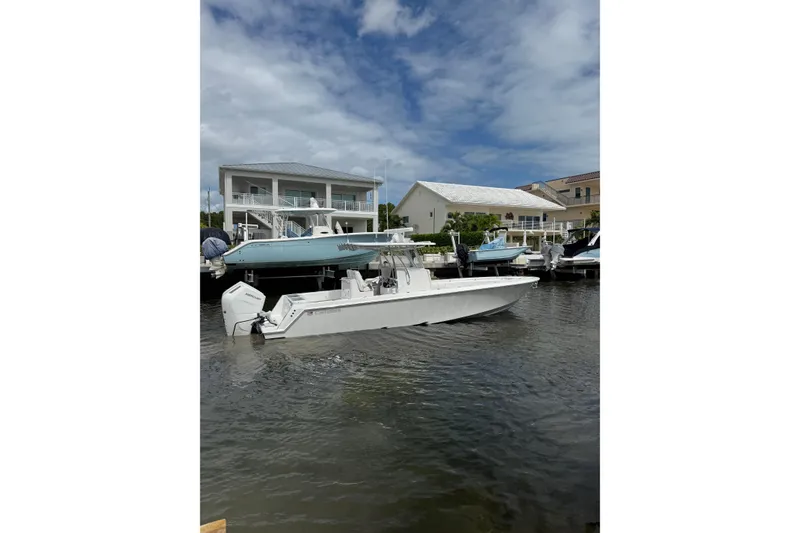 Slide: The Image of 2024 Contender 32 ST boat docked near waterfront homes under a cloudy sky. - 18