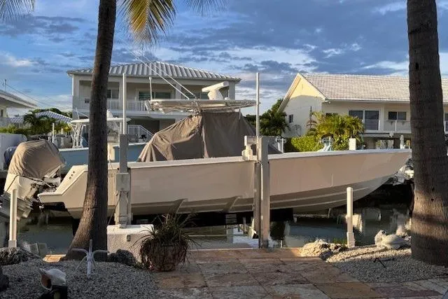 Slide: The Image of 2024 Contender 32 ST boat docked between palm trees in a residential marina. - 2
