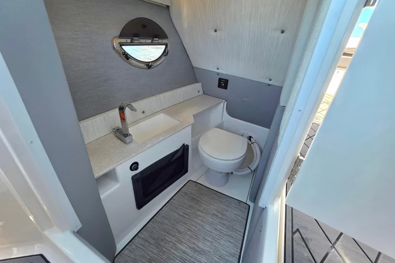 Slide: The Image of 2024 Cobalt R8 Outboard boat interior bathroom with sink, toilet, and porthole window. - 29