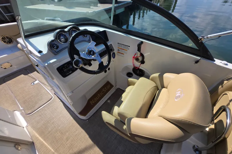 Slide: The Image of 2020 NauticStar 223 DC boat interior with steering wheel and beige seating. - 10