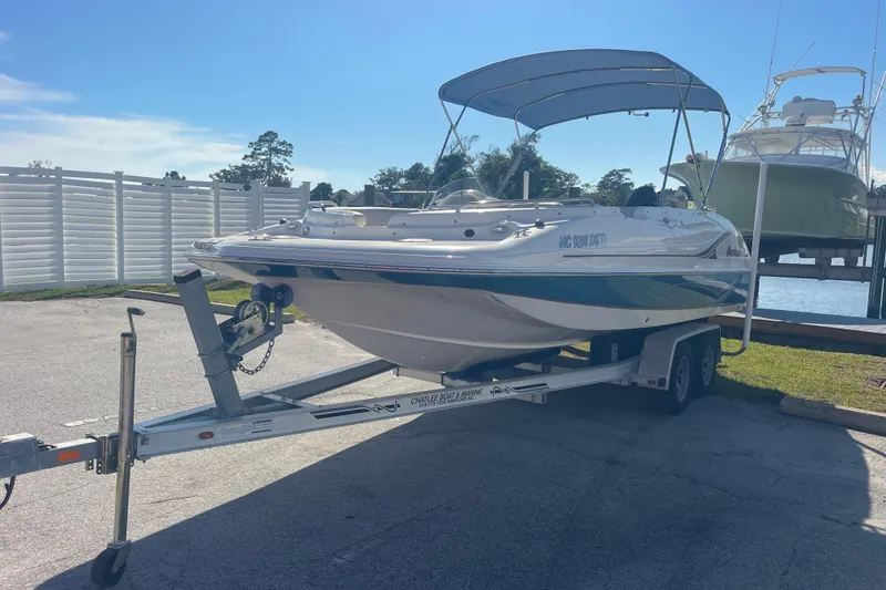Slide: The Image of 2006 Hurricane FunDeck GS 202 OB boat on trailer, parked near water under clear sky. - 2