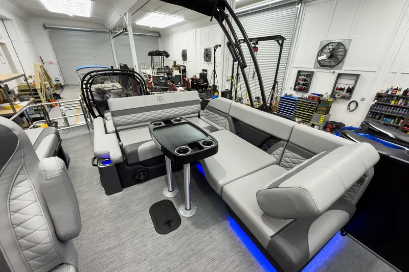 Slide: The Image of 2026 Godfrey Monaco 23' Tritoon interior with luxurious seating and modern design in a workshop. - 31