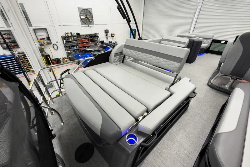 Slide: The Image of 2026 Godfrey Monaco 23' Tritoon with luxurious flip lounge seating in a workshop setting. - 37