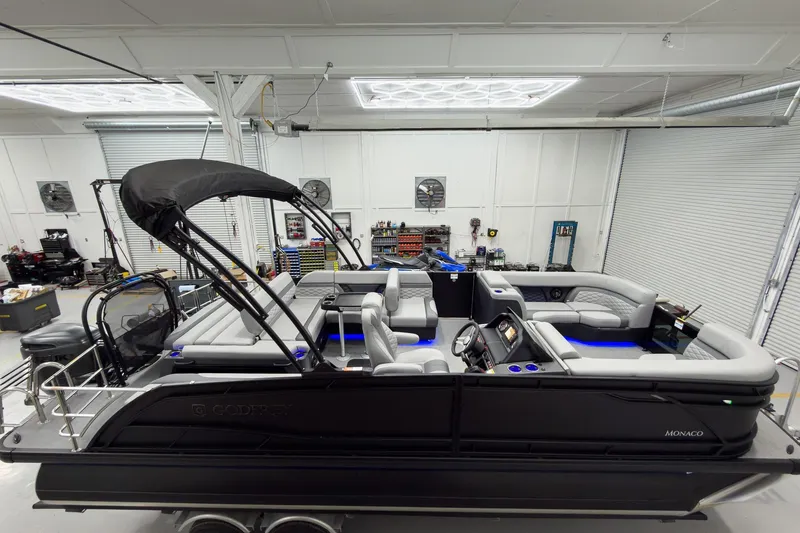 Slide: The Image of 2026 Godfrey Monaco 23' Tritoon with flip lounge, showcased in a spacious indoor setting. - 6