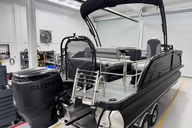 Slide: The Image of 2026 Godfrey Monaco 23' Tritoon with Suzuki engine in a workshop setting. - 7