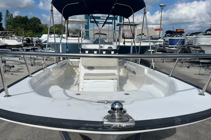 Slide: The Image of 2022 Boston Whaler 170 Montauk boat with canopy, docked in a marina under a cloudy sky. - 12