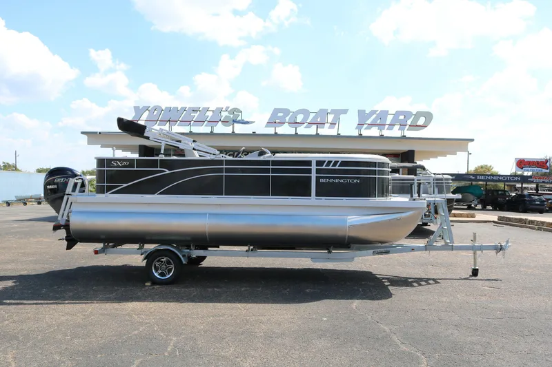 The Image of 2026 Bennington 20SXSNP Rear Fish pontoon boat on trailer, parked outside dealership. - 0