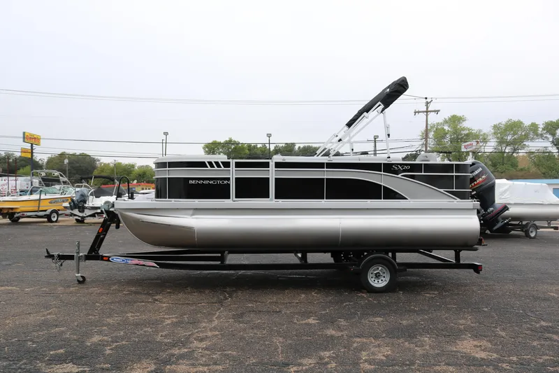 Slide: The Image of 2026 Bennington 20SXSNP REAR FISH pontoon boat on trailer, parked outdoors. - 4