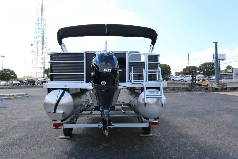 Slide: The Image of 2026 Bennington 20SXSNP REAR FISH pontoon boat with outboard motor, parked outdoors. - 6