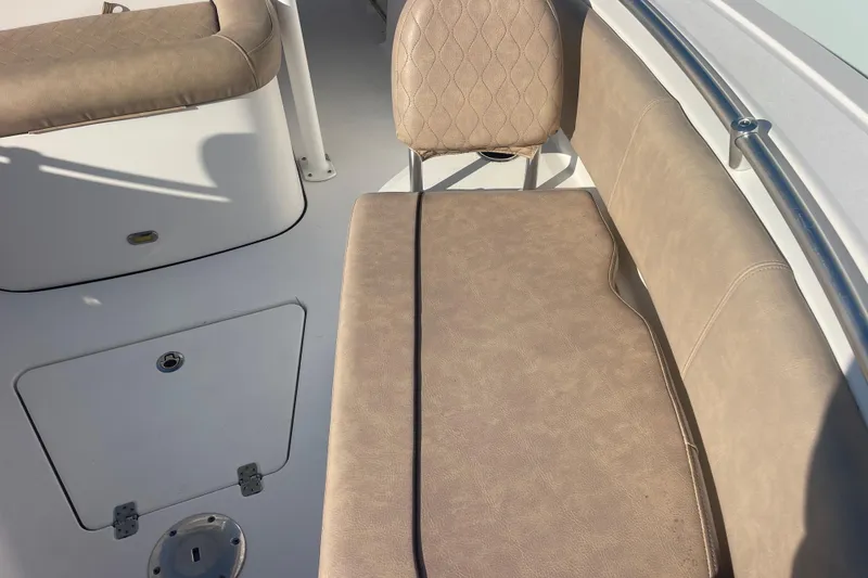 Slide: The Image of 2019 Sportsman Open 242 Center Console boat interior with beige seating and storage compartment. - 15
