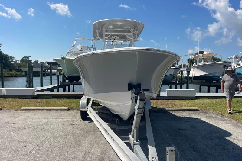 Slide: The Image of 2019 Sportsman Open 242 Center Console boat on trailer, dockside, under clear blue sky. - 2