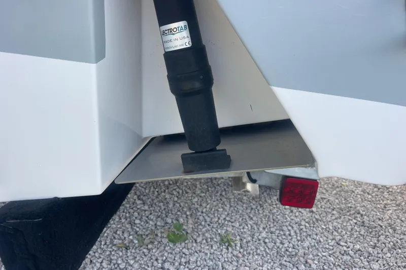 Slide: The Image of 2019 Sportsman Open 242 Center Console boat trim tab detail on gravel surface. - 41