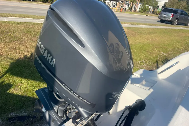 Slide: The Image of 2019 Sportsman Open 242 Center Console with Yamaha outboard motor, parked on grass. - 45