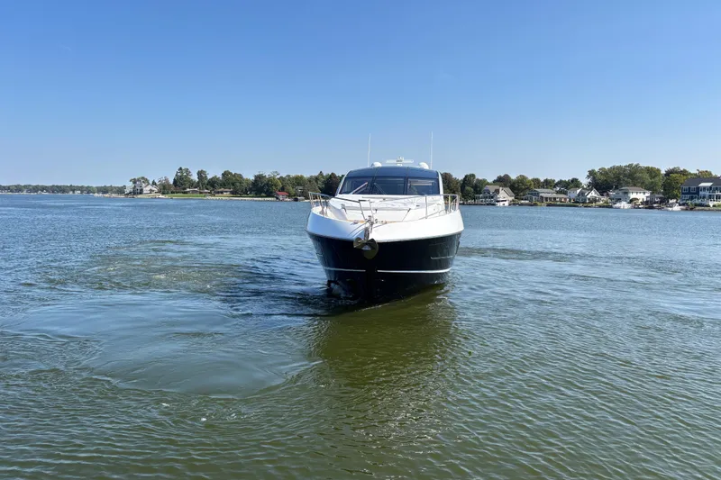 Slide: The Image of 2018 Sunseeker Predator 74 yacht cruising on a calm lake with houses in the background. - 11