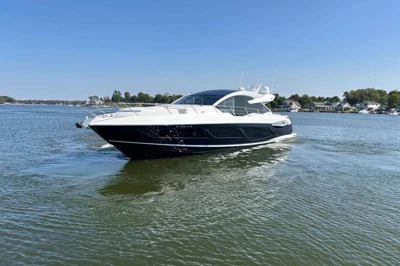 Slide: The Image of 2018 Sunseeker Predator 74 yacht cruising on a serene lake under a clear blue sky. - 9