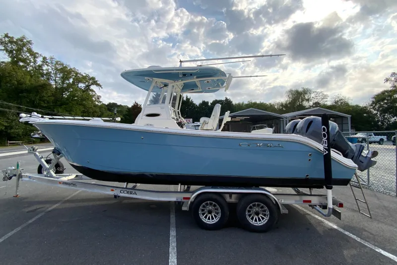 Slide: The Image of 2023 Cobia 262 Center Console boat on trailer, parked outdoors under cloudy sky. - 11