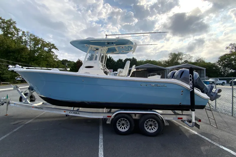 Slide: The Image of 2023 Cobia 262 Center Console boat on trailer, parked outdoors under cloudy sky. - 12