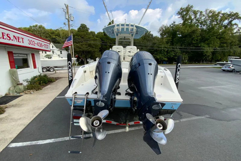 Slide: The Image of 2023 Cobia 262 Center Console boat with dual outboard motors in a parking lot. - 15