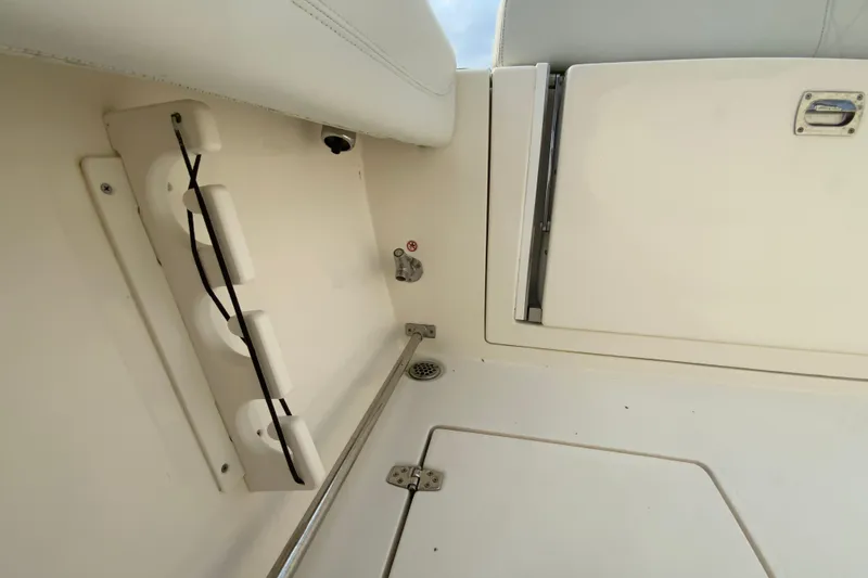 Slide: The Image of 2023 Cobia 262 Center Console interior detail with storage compartment and rod holders. - 25