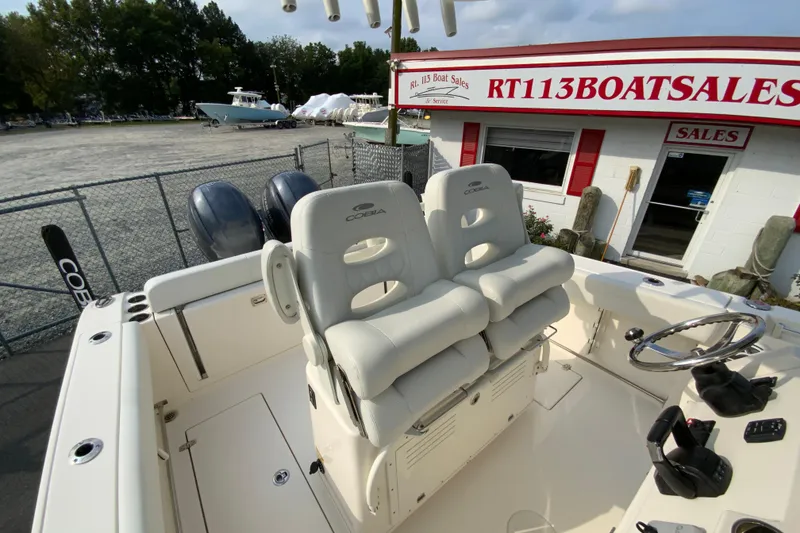 Slide: The Image of 2023 Cobia 262 Center Console boat at dealership, featuring dual seats and steering console. - 28